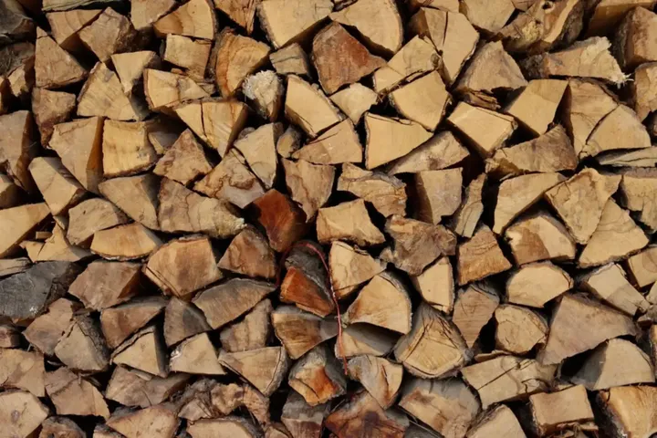 Leña de naranjo partida y apilada, de madera clara
