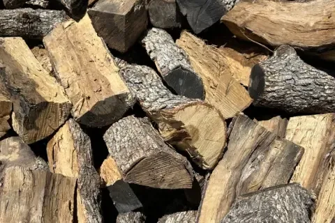 Leña de roble partida y apilada, con corteza gruesa