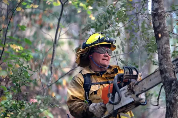 Persona con equipo de protección usando una motosierra pequeña